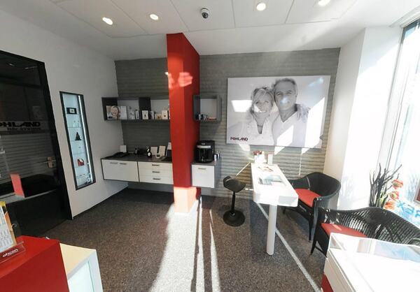 Modern eingerichtetes Hörakustik-Fachgeschäft mit Beratungstisch und Werbeplakat.